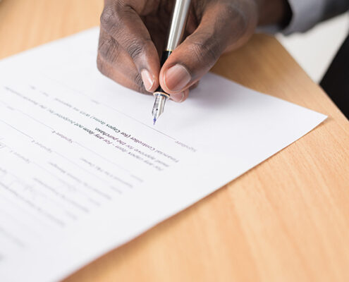 A hand signing a document