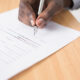 A hand signing a document