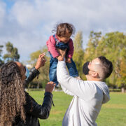 Two parents holding a baby outside.