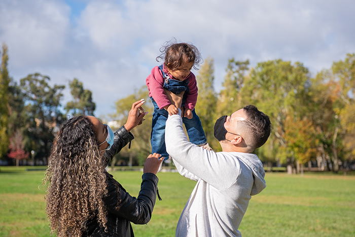 Two parents holding a baby outside.