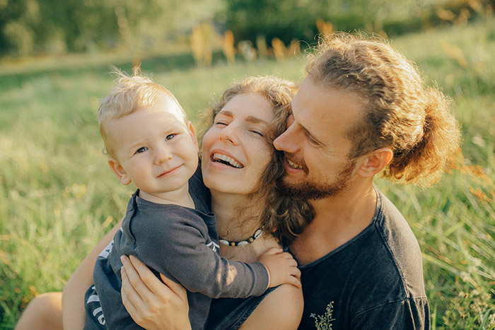 A picture of a smiling mother, father, and young child.